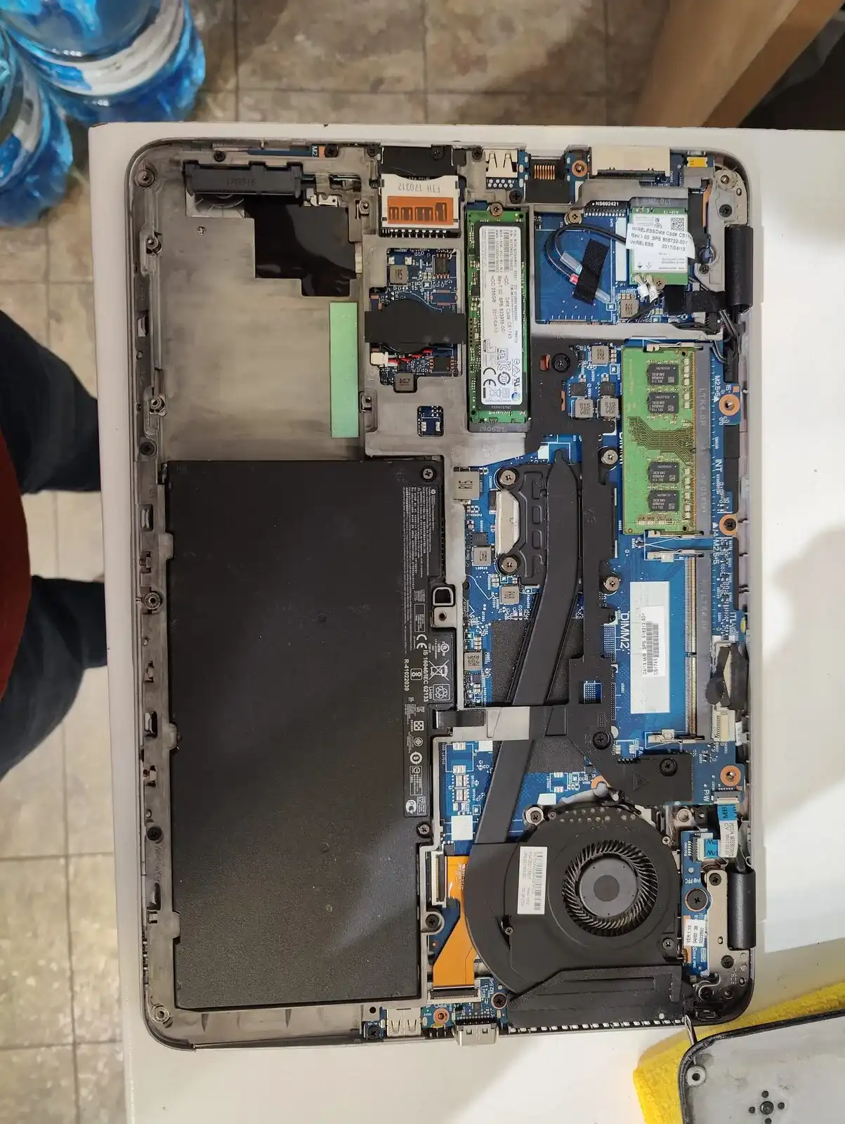 Open laptop showing its battery, memory, cooling fan, and internal components
