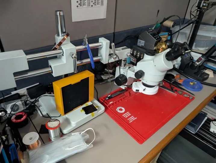 Electronics repair bench with microscope, tools, and an open device